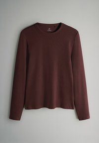 Burgundowa koszulka z długim rękawem, wykonana z gładkiego materiału, z okrągłym dekoltem i prążkową fakturą. Prosty dół z detalami w postaci bocznych rozcięć.