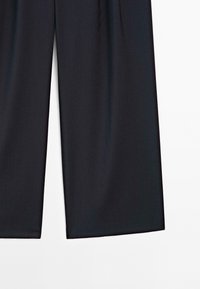 Zwarte wijde broek met een strakke, gladde textuur, met een nette snit en zonder zichtbare hardware. De taille is elastisch voor comfort.