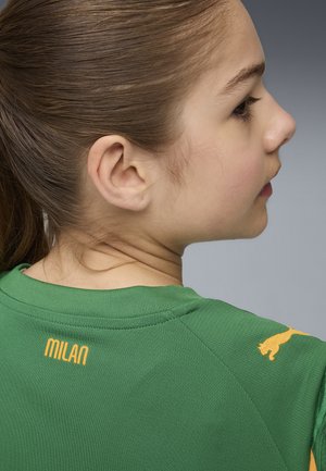 Maglietta atletica verde con collo a girocotolo a coste; "MILAN" in giallo sul retro, logo Puma in giallo sulla spalla, texture della stoffa liscia.
