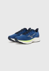 Modré športové topánky z sieťoviny s textúrovaným dizajnom, zelenými akcentmi a hrubou bielou podrážkou so ziggzagovým vzorom.