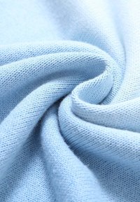 Tissu bleu clair tricoté en une spirale douce, montrant une texture fine et des coutures détaillées en vue rapprochée.