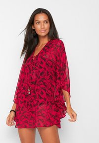 Tunica rossa con un motivo floreale nero, scollatura a V e maniche larghe. Realizzata in tessuto leggero e trasparente con una texture leggermente semi-trasparente.
