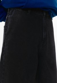 Sorte denimjeans med en afslappet pasform, der har en mellemhøj talje, forlommer og en subtil tekstur. Stoffet virker blødt og slidstærkt.