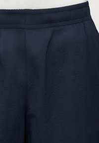 Κοντινή λήψη παντελονιού με ελαστική μέση σε ναυτικό μπλε, με ορατές ραφές και υφή υφάσματος.