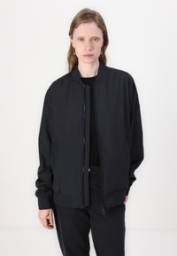 Black bomber jacket with a smooth fabric, ribbed cuffs and hem, front zipper closure, and side pockets. Simple, minimalistic design.