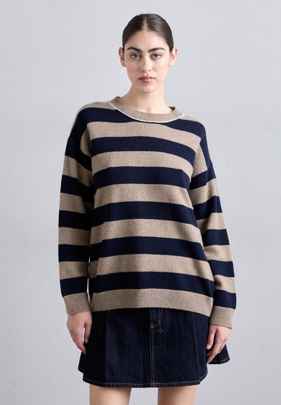 Jersey de punto a rayas en azul marino y beige con cuello redondo y puños acanalados, combinado con una falda de mezclilla que presenta un sutil detalle de costura.