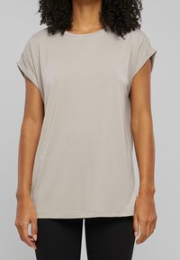 Lys beige kortærmet t-shirt med rund halsudskæring og rullede ærmer, lavet af blødt stof, med en afslappet pasform og lige kant.