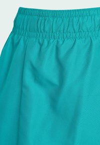 Tyrkysová sukňa s elastickým pásom, hladkým, netextúrovaným povrchom a zhromaždením, ktorá predstavuje ľahký a ležérny dizajn.
