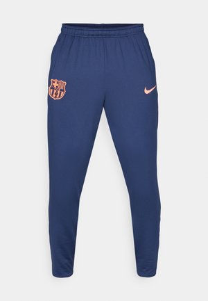 Marineblå atletiske bukser lavet af glat stof, med et orange FC Barcelona-logo og en lille orange Nike swoosh på hoften.