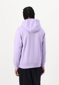 Ljuslila hoodie med en känguruficka, ribbade ärmar och justerbar huva. Slät tyg med regular fit, bärs med mörka byxor.