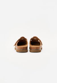 Zapatos marrones de cuero sin cordones con interiores acolchados, punteras redondas y correas ajustables. Presentan una parte superior texturada y suelas de goma resistentes.
