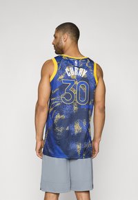 Blå og gul basketballtrøye med teksturert grafisk design. Har spillerens navn "CURRY" og nummer "30" på baksiden.