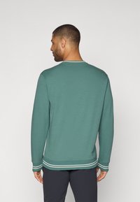 Felpa verde a maniche lunghe con scollo rotondo, dettagli a strisce bianche a contrasto sui polsini e sull'orlo, e una texture morbida.