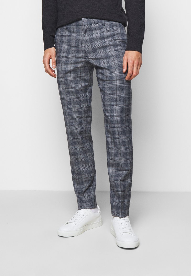 Grå rutiga byxor med en skräddarsydd passform, med ett rutig mönster och subtil textur. Kombineras med vita sneakers för en avslappnad look.