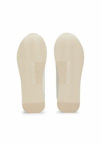 Twee schoenzolen, lichtbeige met een gestructureerd visgraatpatroon, met een verticale logo-detail nabij het hielgebied.