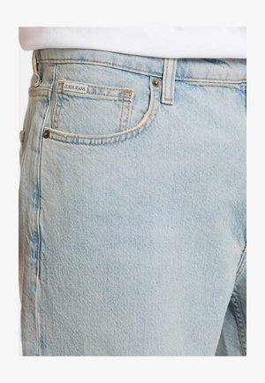 Svetlo modri kavbojki z bledim zaključkom, ki imajo majhno nalepko z logotipom, pet žepov, kovinske zakovice in klasičen raven kroj.