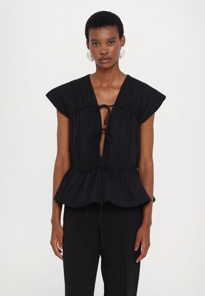 Schwarze Peplum-Bluse mit kurzen Ärmeln, ausgestattet mit einem vorderen Bindeband und geraffter Textur. Trägt man über schwarzen Hosen, minimalistisches Design.