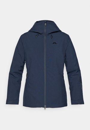 Casaco impermeável azul marinho com capuz, fecho frontal, cordões ajustáveis e bolsos laterais com fecho. Textura suave, design minimalista.