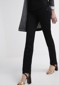 Svarta denimbyxor med rak passform, som har en klassisk femficksdesign och subtila sömnadsdetaljer. Kombineras med guldklacksandaler.