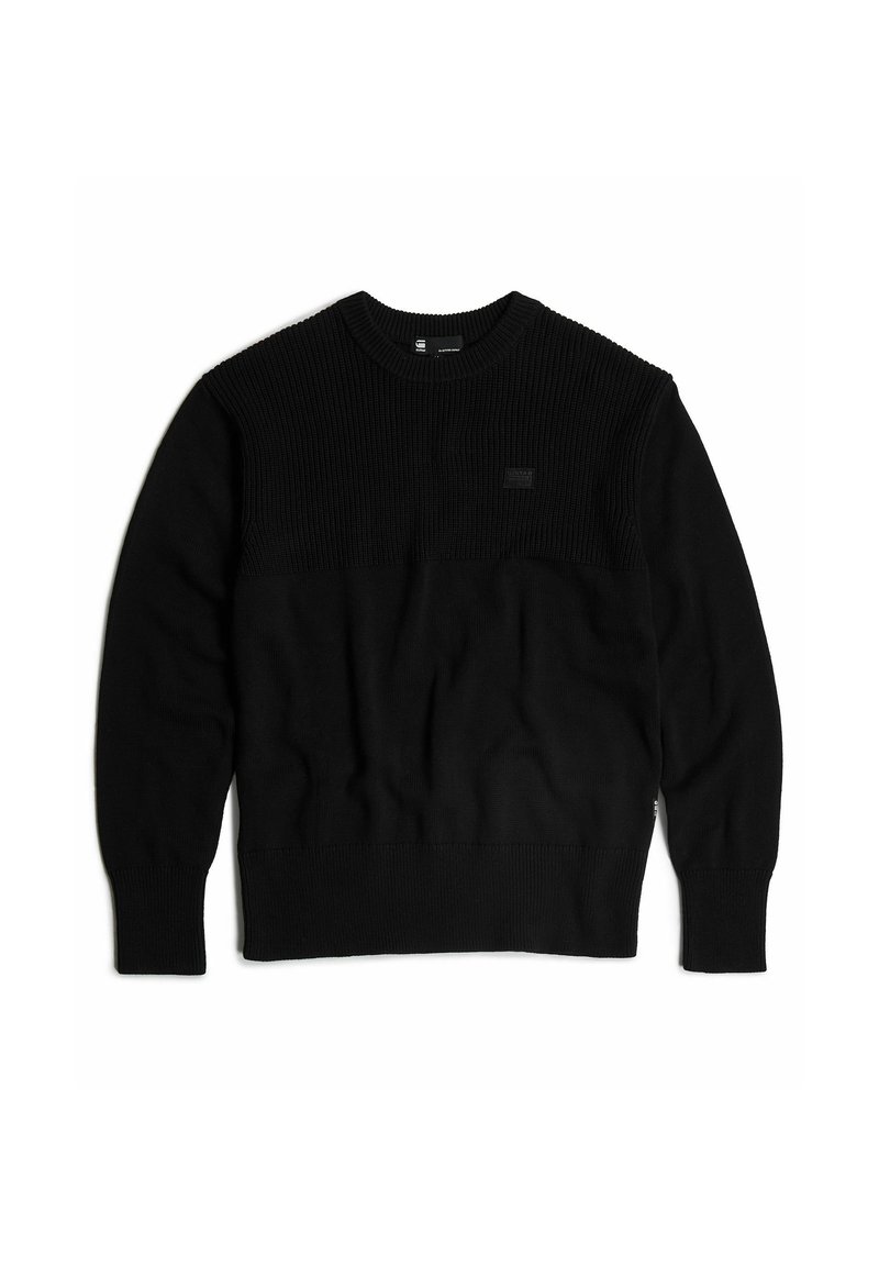 Suéter negro con textura acanalada en los hombros, cuerpo liso, cuello redondo y parche de logo en el pecho. Mangas largas y puños elásticos.