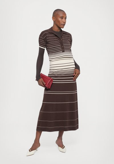 Braun- und cremefarbener gestreifter Kleid mit Kragen und Knöpfen. Lange Ärmel mit tailliertem Oberteil und ausgestelltem Rock. Rote Clutch und weiße Schuhe.