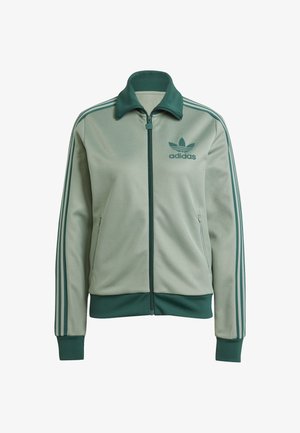 Lichtgroene adidas-jas met rits, hoge kraag en drie donkergroene strepen langs elke mouw. Beschikt over een logo op de linkerkant van de borst en zijzakken.