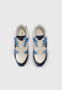 Un paio di sneakers crema con accenti blu e navy, orli oro, lacci e patch del logo sui lati, viste dall'alto su sfondo bianco.