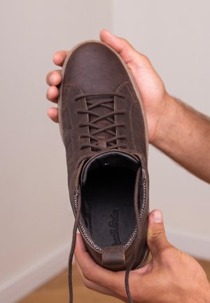 Bruine leren sneaker met gestructureerd oppervlak, ronde neus en vetersysteem. Het interieur is donker met een gevoerde voering.