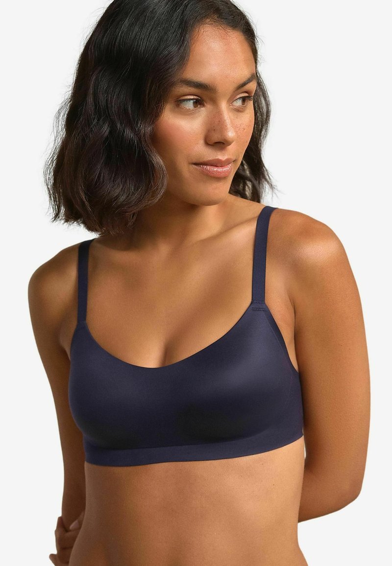 Marineblauwe draadloze bralette met dunne banden, een gladde structuur en een ronde halslijn. Zachte stof met minimale hardware details.