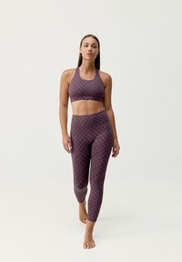 Conjunto de sujetador deportivo y leggings en mauve oscuro con una sutil textura estampada. Tejido suave, corte ajustado y diseño minimalista.