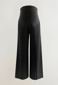 Pantaloni negri cu o croială evazată, cu talie înaltă, confecționați dintr-un material neted. Prezintă plii verticale pentru un plus de dimensiune.