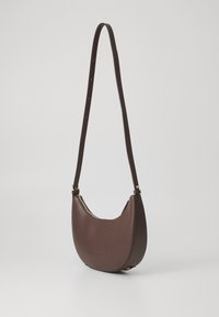 Borsa a spalla in pelle marrone con una forma curva, dotata di una cerniera dorata e di una tracolla regolabile. Texture liscia, design minimalista.