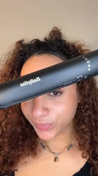 Zwarte stijltang met een strak ontwerp, voorzien van een digitaal display, temperatuurinstellingen en het Babyliss-logo.