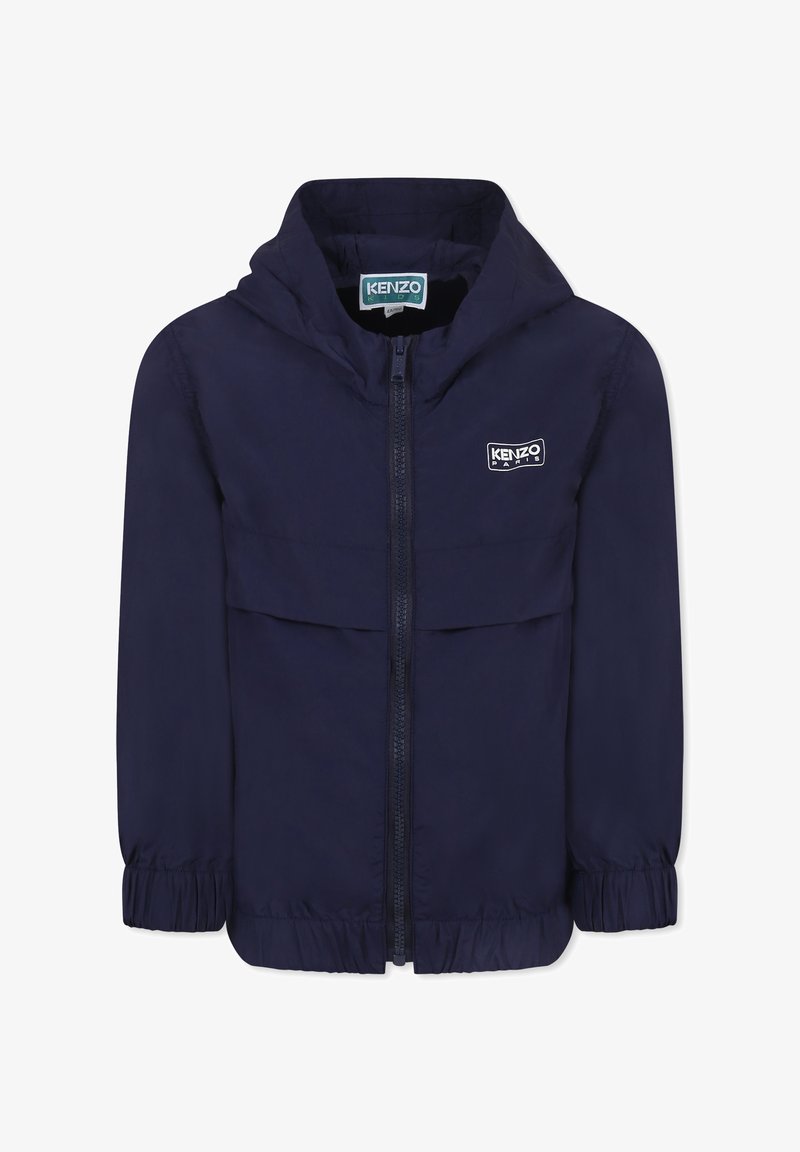 Giacca blu navy con cappuccio, chiusura con zip, polsini elasticizzati e un patch con logo sul petto. Tessuto leggero e dalla texture liscia.