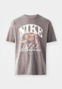 Grå bomulds T-shirt med et hvidt "Nike" logo og en orange grafik af en bevinget hest med "atletik" nedenunder, rund hals design.