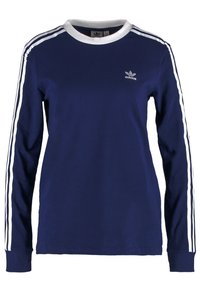 Laivastonsininen pitkähihaisen paita puuvillasta, jossa on valkoiset raidat hihoissa ja valkoinen ribbikaulus. Rinnassa on brodeerattu logo.