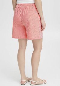 Pantaloni corti a righe rosse e bianche con vita elastica, dotati di tasche laterali e una vestibilità comoda, realizzati in tessuto leggero.