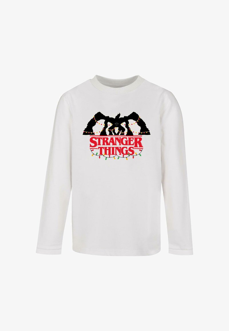 Camisa de manga larga blanca con un gráfico negro de personajes adornados con luces de colores de festividad y la inscripcióm en rojo bold "STRANGER THINGS".