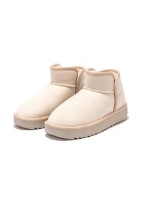 Botas de tobillo de ante beige con puntera redondeada, cuello acolchado y suela de cuña texturizada. Incluye costura tonal y un acabado de superficie suave.