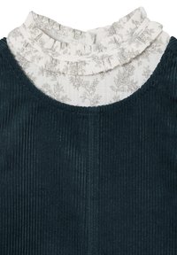 Dunkelgrünes Cordkleid mit hohem Ausschnitt, das mit einem weißen Rüschensaum mit einem grauen Blumenmuster versehen ist. Strukturierte Stoffdetails sind sichtbar.