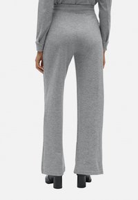 Pantalones de algodón gris de pierna ancha con un acabado texturizado, que cuentan con una cinturilla elástica y un ajuste relajado, combinados con zapatos de tacón negros.