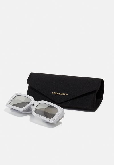 Lunettes Dolce & Gabbana avec monture blanche ornée de strass, verres gris et étui en tissu noir avec logo doré.
