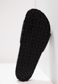 Sole de pantof din cauciuc negru cu un model în valuri, având o suprafață texturată pentru aderență. Vedere laterală care ilustrează forma și designul pantofului.