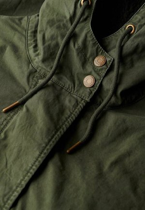 Green hooded jacket with a textured fabric, featuring bronze snap buttons and drawstrings with metal tips. Close-up view of design details.