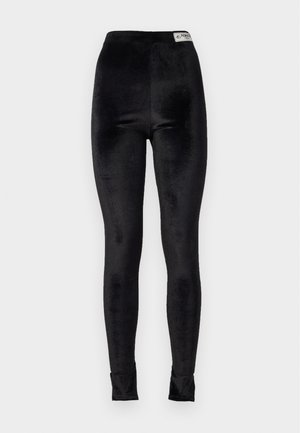 Black velvet leggings with a high waist, smooth texture, and fitted design; includes a brand tag at the waistband.