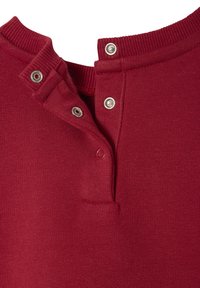 Roter Strickpullover mit einem gerippten Kragen und zwei Druckknöpfen am Halsausschnitt. Der Stoff ist glatt mit einer leicht strukturierten Oberfläche.