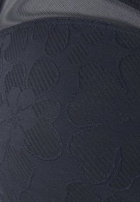 Marineblaue Textilie mit floralem Muster, das erhöhte und strukturierte Elemente aufweist. Glatte Oberfläche mit subtiler Glanz. Ideal für Bekleidungsnutzung.
