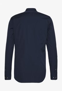 Camisa de manga larga navy con cuello puntiagudo, textura lisa, puños con botón y dobladillo redondeado. La tela parece ligera y ligeramente brillante.
