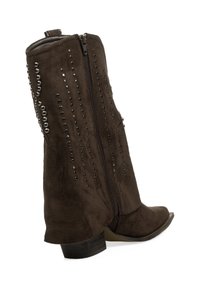 Botín de ante marrón hasta el tobillo con puntera afilada, que presenta un cierre de cremallera lateral y tachuelas decorativas de metal a lo largo del eje exterior. Tacón bajo y apilado.