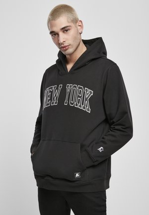 Čierna mikina s kapucňou s nápisom "NEW YORK" veľkými bielymi písmenami. Mäkko tkanina, predná vrecko a logo na rukáve.